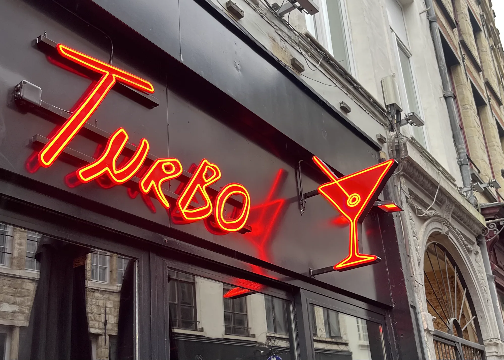 Red-orange neon logo with cocktail glass on the Turbo facade in Antwerp