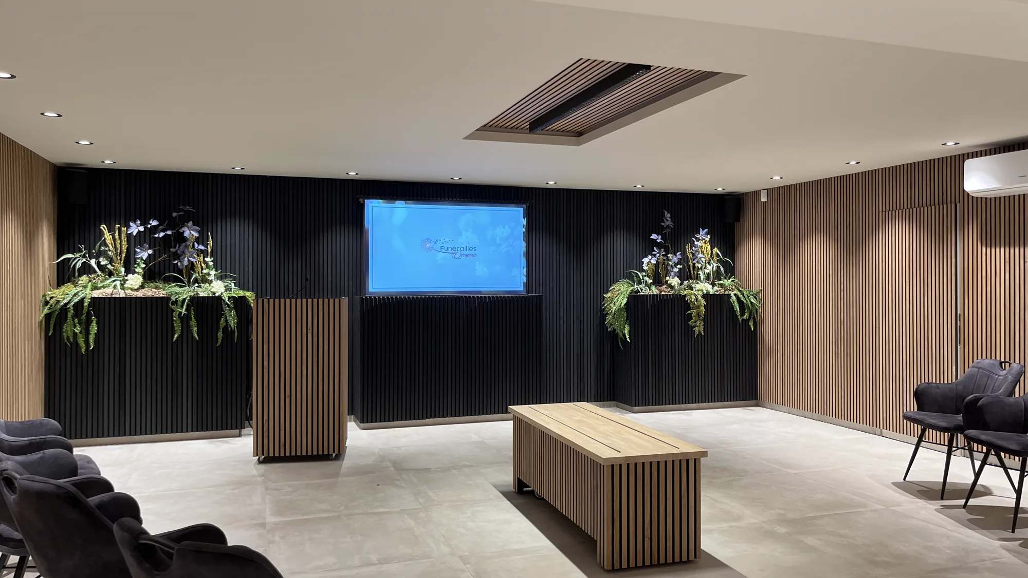Funérailles Deramaix ceremony room with slatted wall, screen and flowers