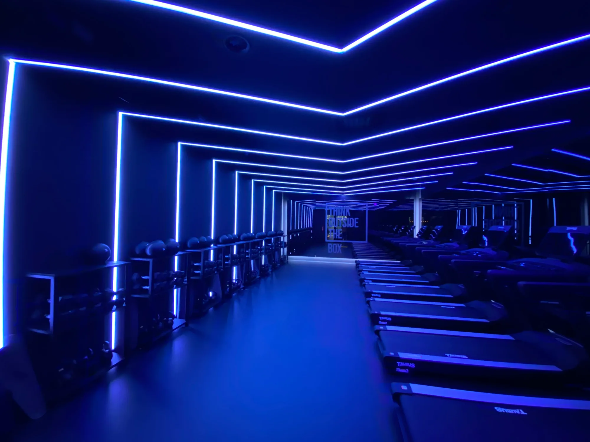 Spinning studio in blue light with LED lines across walls and ceiling
