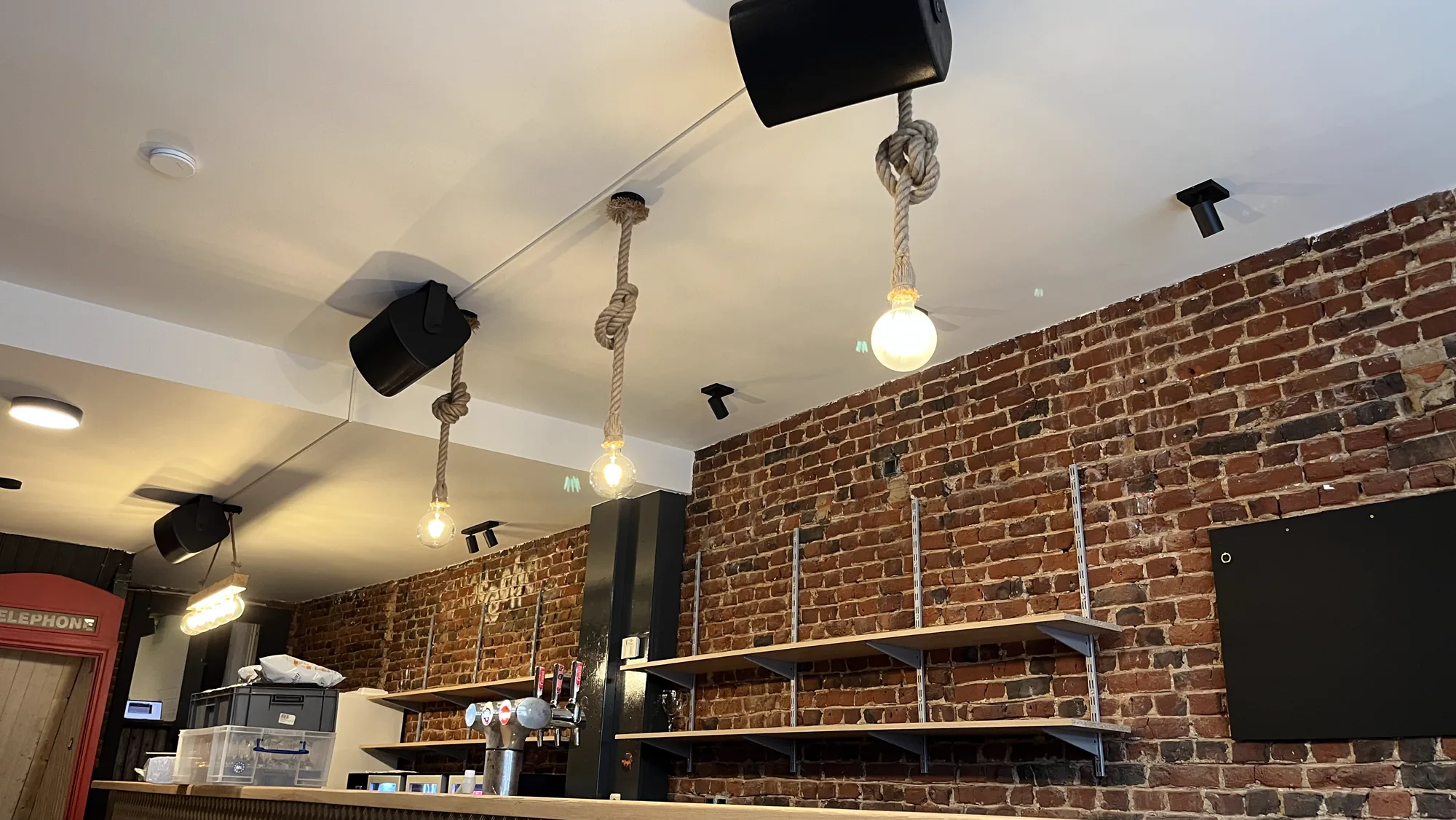 Ninove youth centre bar with ceiling loudspeakers and a brick wall
