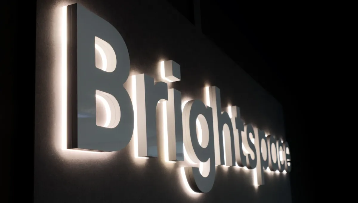 Backlit Brightspace letters with a soft halo on a dark wall