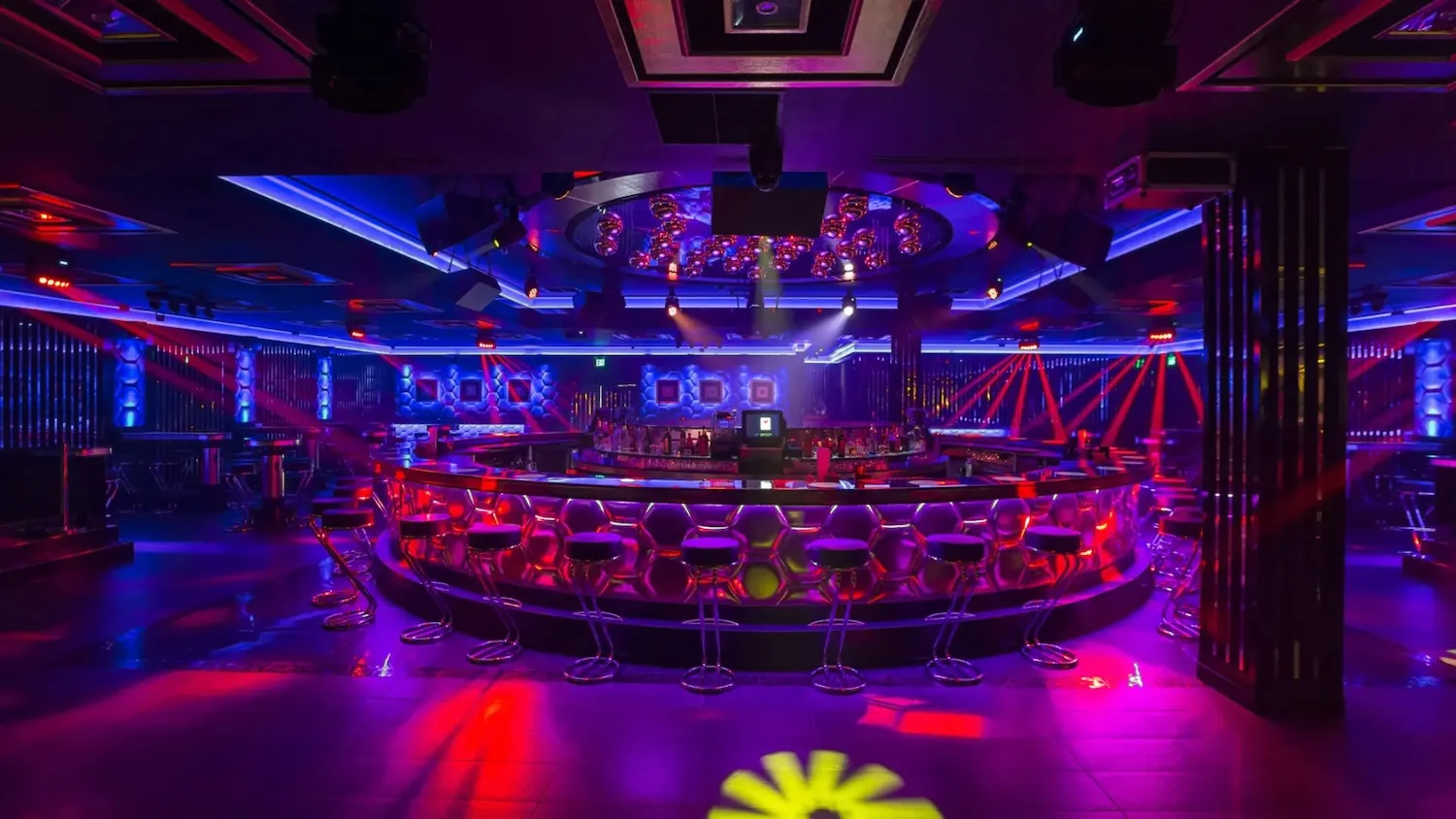 Nightclub in purple and red light around a circular bar and dance floor