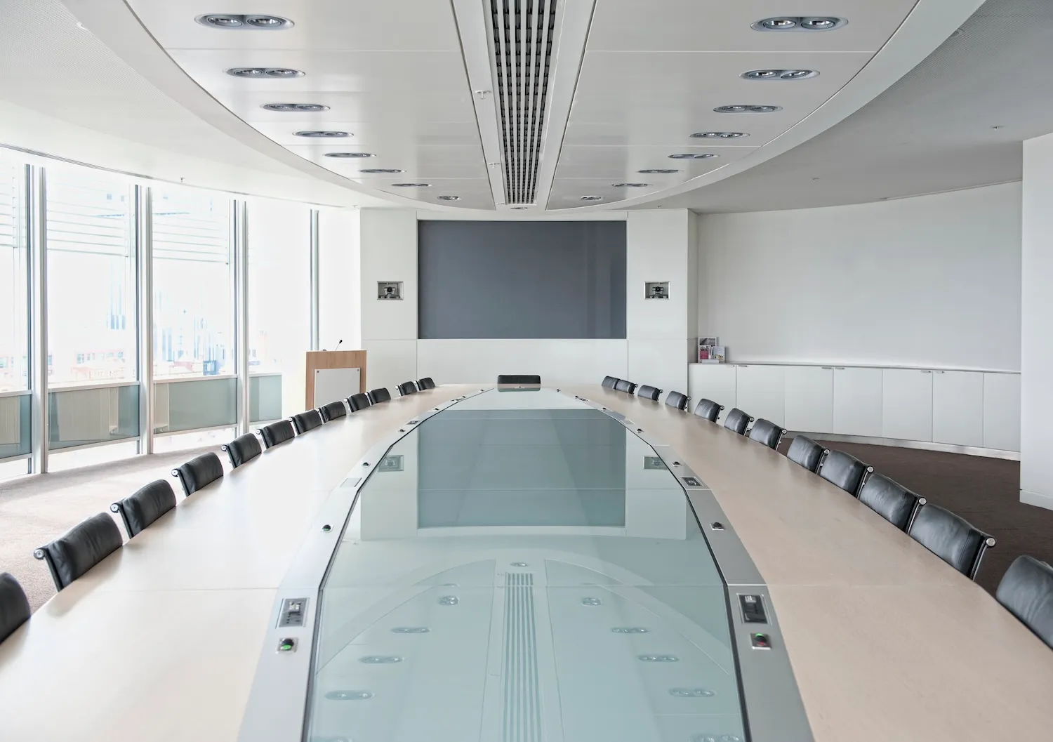 Boardroom with a long table and a screen for video conferencing